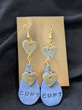 gold hearts dangle over a blue teardrop that says cunt